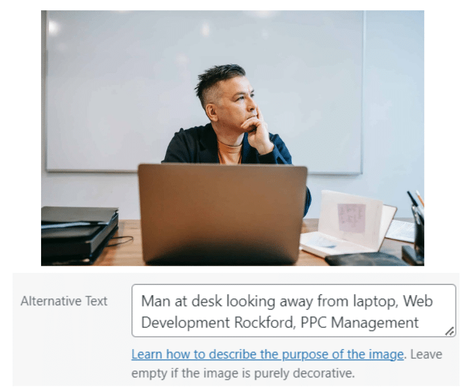 Man at desk looking away from laptop - Image Optimization in SEO